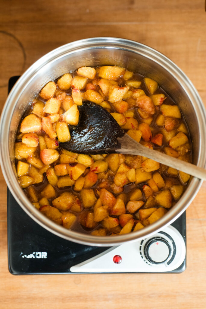 Ingredients simmering together on stovetop for old fashioned peach cobbler.