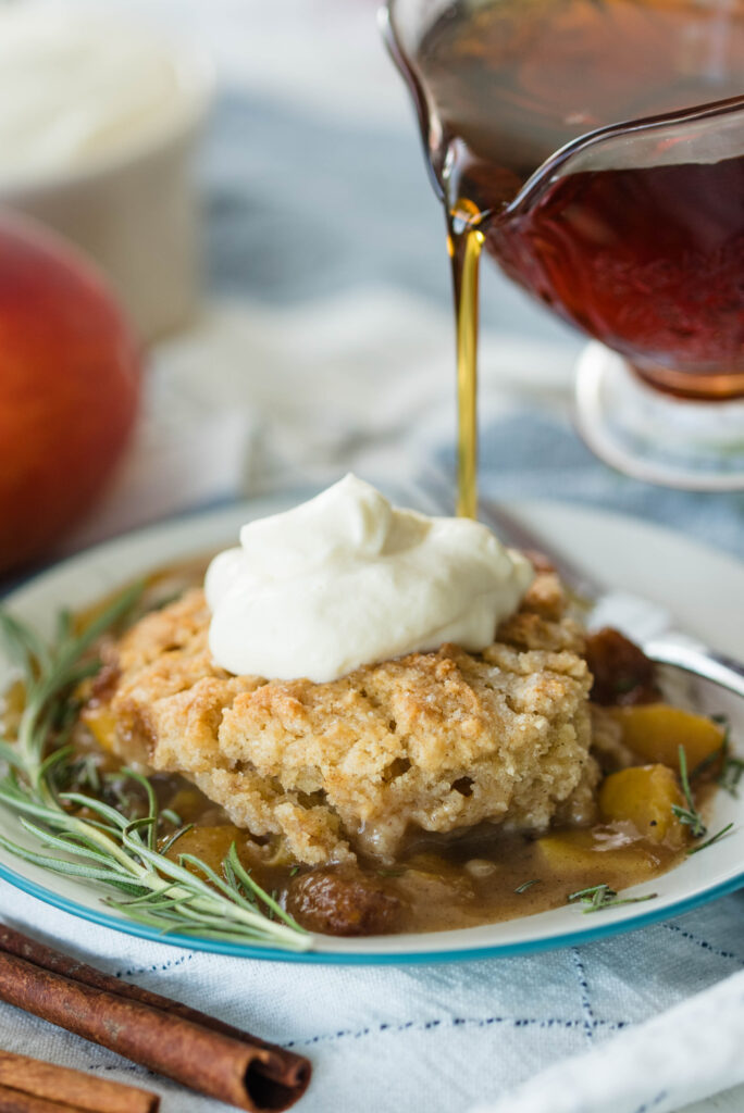 Maple syrup drizzled on top of old fashioned peach cobbler.