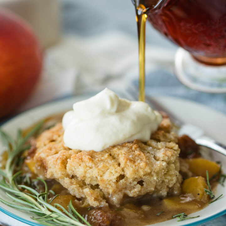Maple syrup drizzled on top of old fashioned peach cobbler.