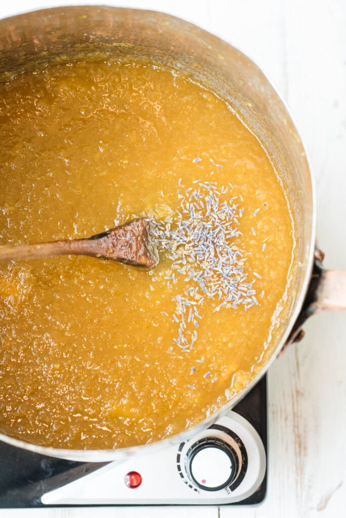 Peach lavender jam with dried lavender being stirred in.