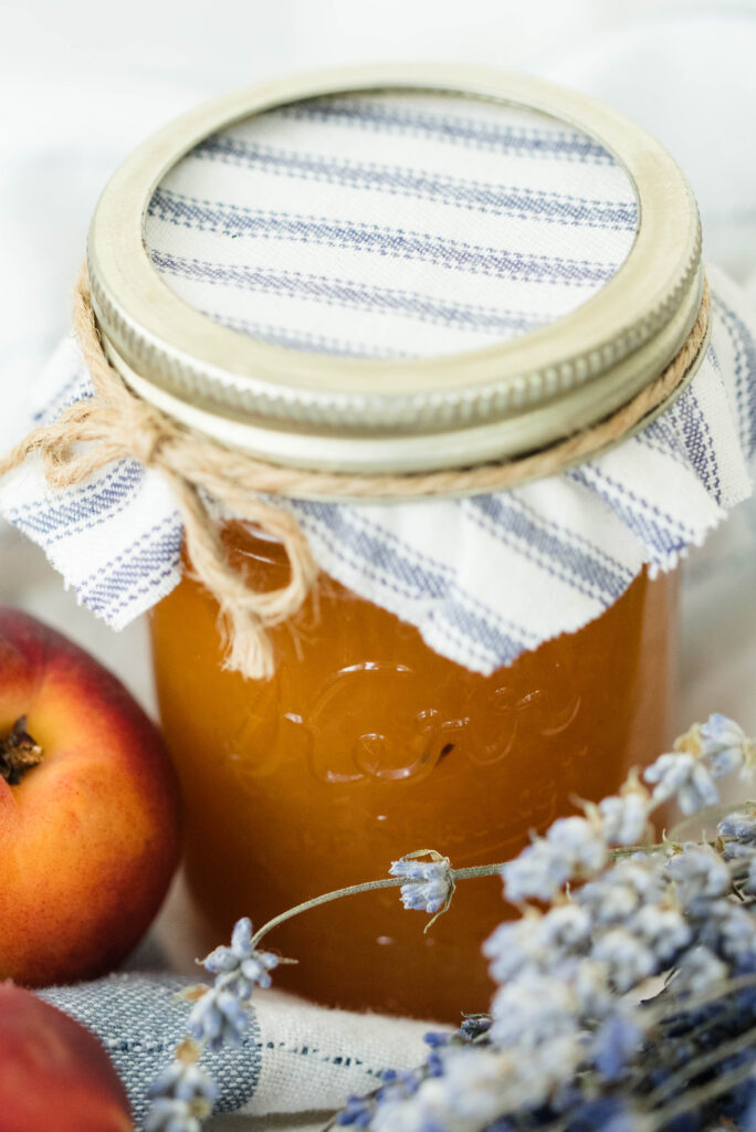 Jar of peach lavender jam covered with a decorative cloth.