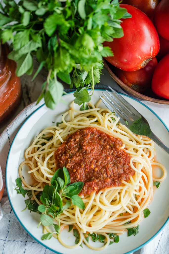 Pasta sauce for canning on top of a plate of noodles.