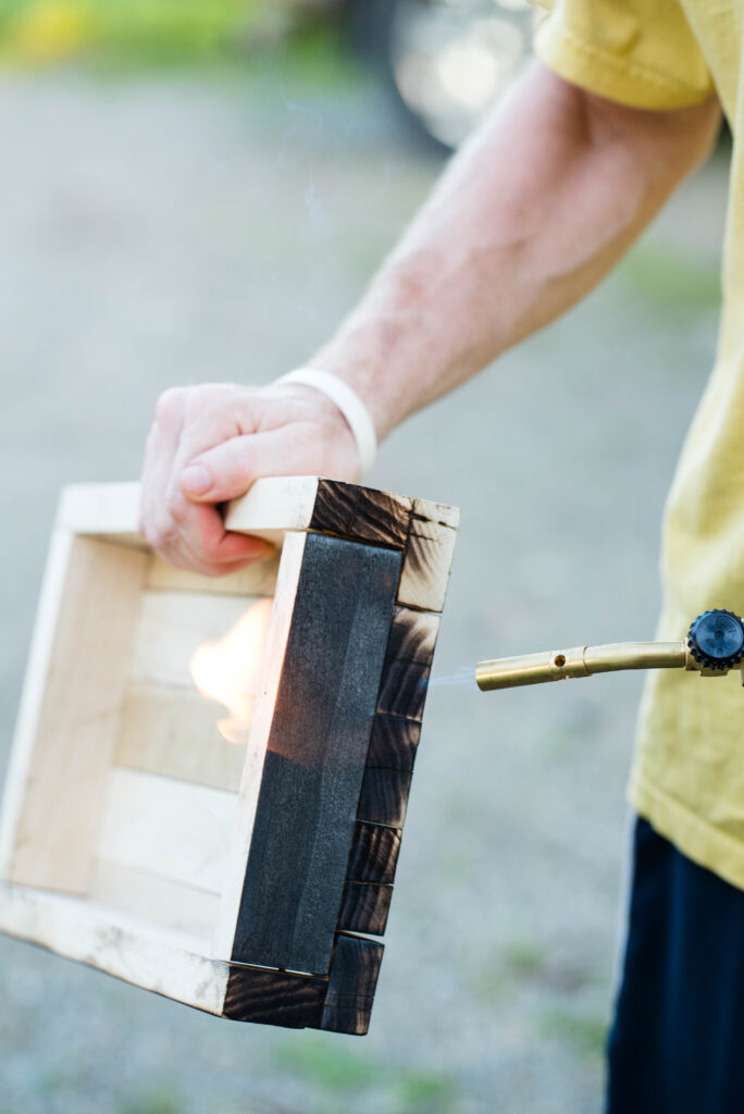 Propane torch charring the outside of a wood box.