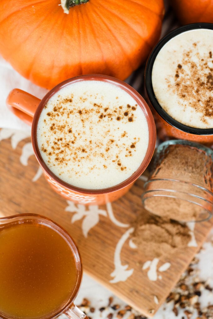 Herbal pumpkin spice latte pictured with fresh pumpkins and homemade pumpkin syrup.