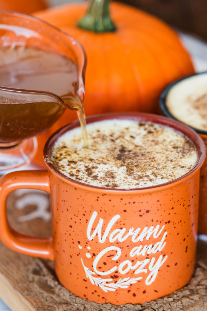 Homemade pumpkin spice syrup being poured into a cup of herbal pumpkin spice latte.