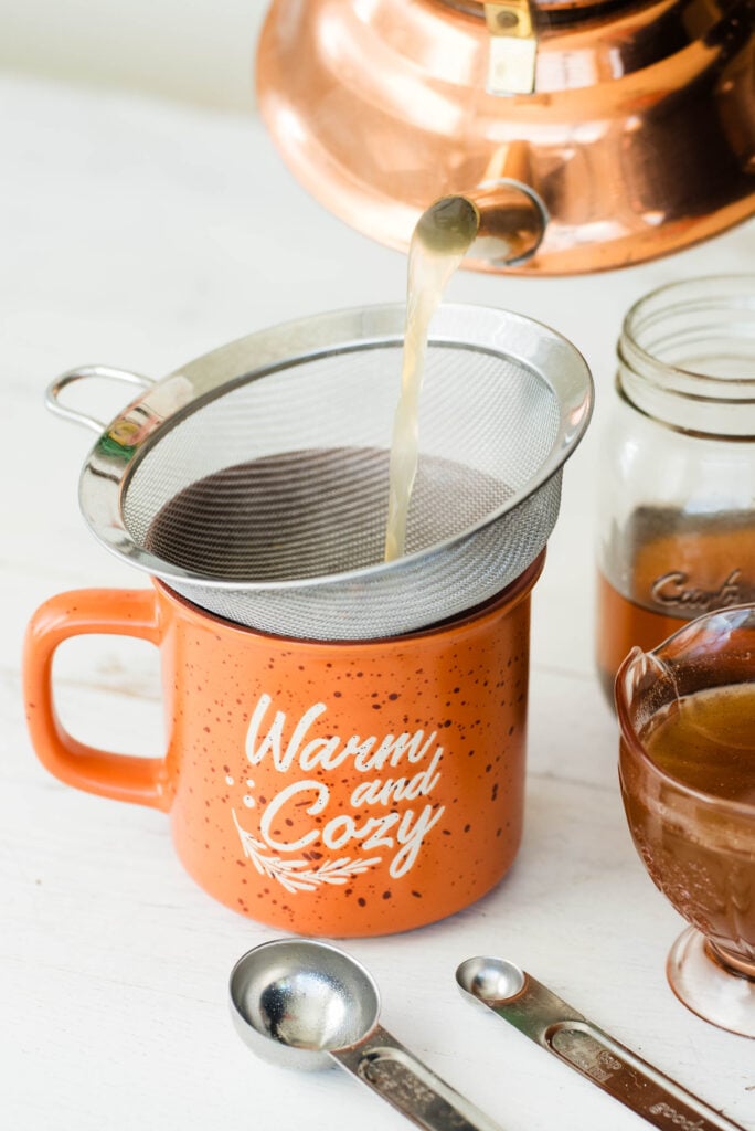 Tea being poured into a mug for an herbal pumpkin spice latte.